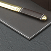 corner detail of brown leather desk pad with white stitched trim